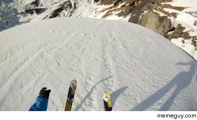 Skiier base jumps next to an avalanche
