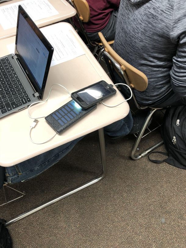 Student tries to charge solar panel external battery using the light from their phone so that they can charge their phone