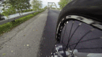 A guy riding his bike across a bridge beam