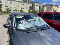 Jim Dwight and Michael on a sun shade in someones car in a parking lot