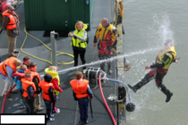 Kids playing with a water hose during coast guard demonstration