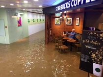 old man continues reading news while starbucks gets flooded 
