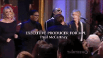 Stevie Wonder reaching for a microphone stand that Paul McCartney knocked over