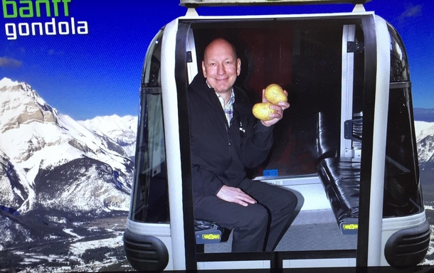 A guy posed for a photo op on a gondola with two potatoes