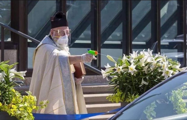 A priest sprays holy water with a water pistol