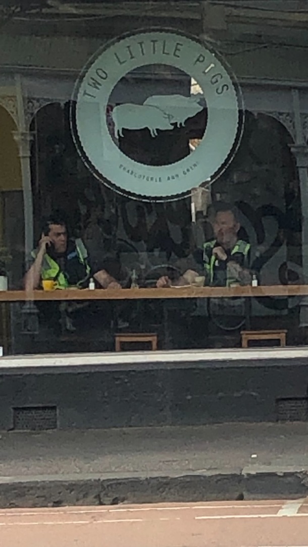 Cafe across from me is called  little pigs There just happened to be  police officers sitting under the sign