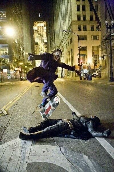 Heath ledger doing a kick flip over Christian bale on set during break
