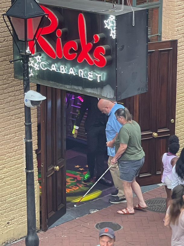 Husband leading blind wife into strip club