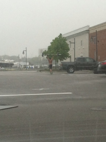 Just some dude lifting weights in the rain in a mall parking lot