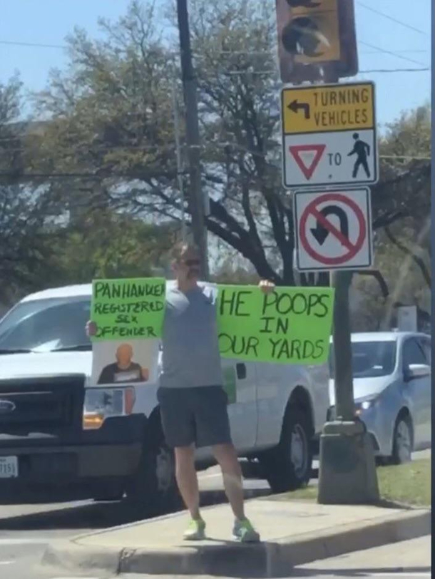 Man holds sign in intersection next to the neighborhood beggar to let drivers know not to give him money because be poops in peoples nearby yards
