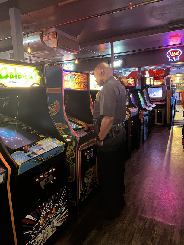 On duty cop playing Miss Pac-Man