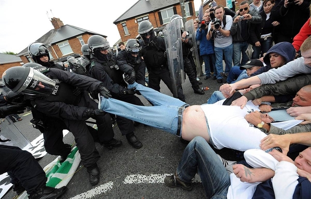Police and rioters come together to help fat man out of trousers