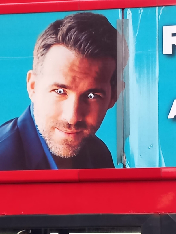 Someone put googly eyes on Ryan Reynolds picture on a bus