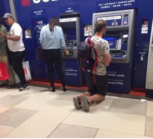 Tall German tourist using an ATM in south-east Asia