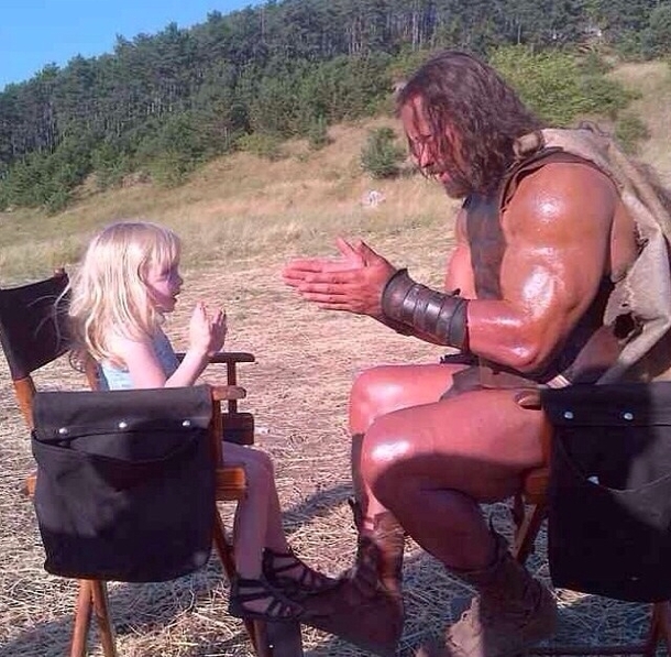 The Rock on set and in costume as Hercules playing party cake with a  year old