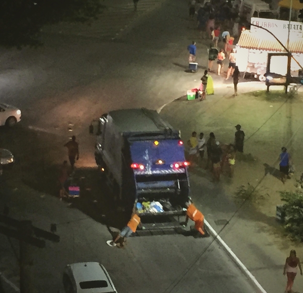 Trashmen surfing on cardboard while on duty