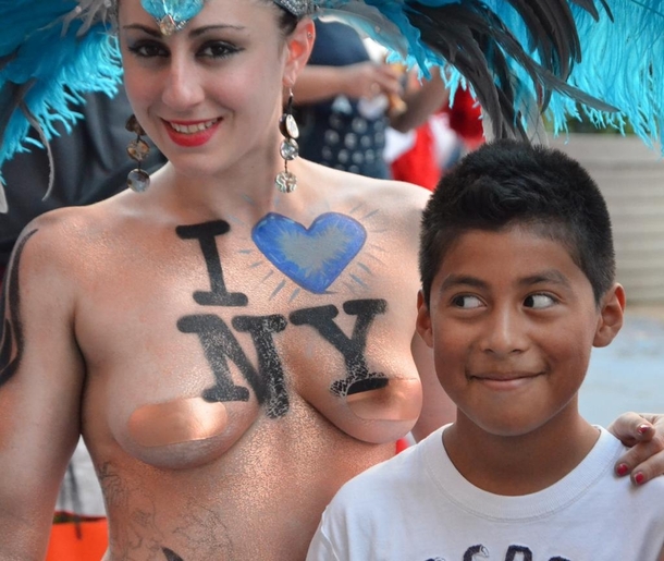 While walking in Times Square a boy takes a picture with a half naked street performer