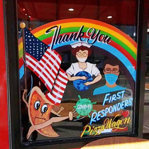 A mural in the window of a pizzeria depicting an anthropomorphic slice of pizza kicking Covids ass