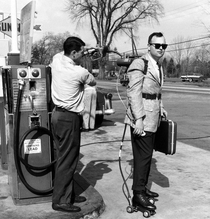 A salesman has his motorized roller skates refueled at a gas station 