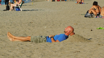 Chillin on the beach with a football for a pillow his head is becoming the same color as the football