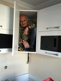 Contractor gets in the cabinet he just built to prove its sturdiness