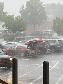 Guy takes the grocery store picnic table umbrella to load his groceries  