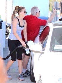 Jennifer Lawrence filling her tank while her dad flicks off paparazzi