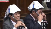 Members of Japans parliament try out the latest in foldable emergency helmets