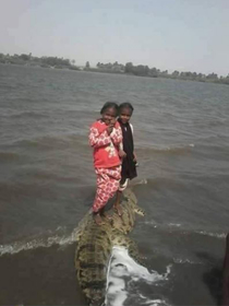 Nubian kids standing on a crocodile scooter