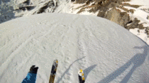 Skiier base jumps next to an avalanche