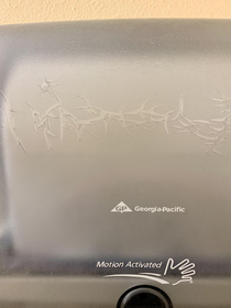 The cracks on this paper towel dispenser look like the logo of a metal band