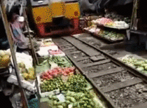 Train passing through a busy vegetable market