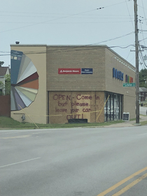 Yesterday someone drove their car into this building Today the owners decided to temporarily cover the damage and leave this message